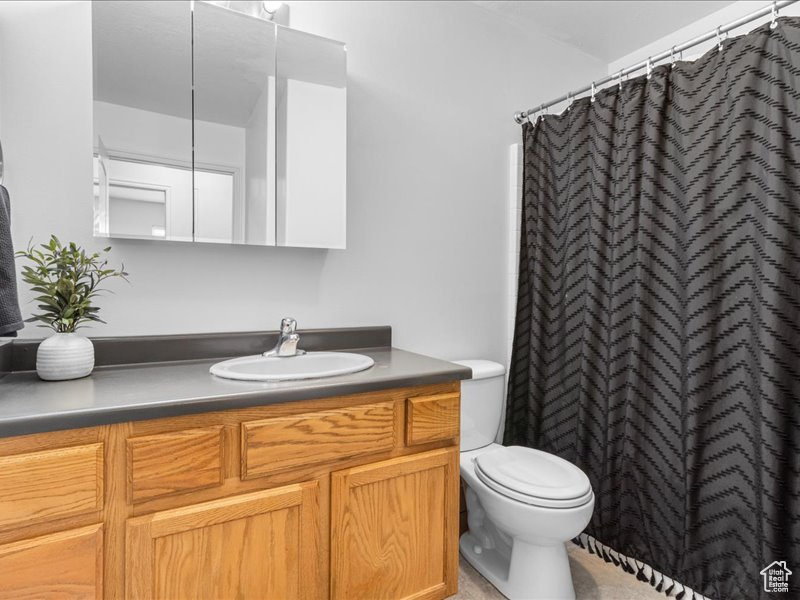 Bathroom with a shower with curtain, vanity, and toilet