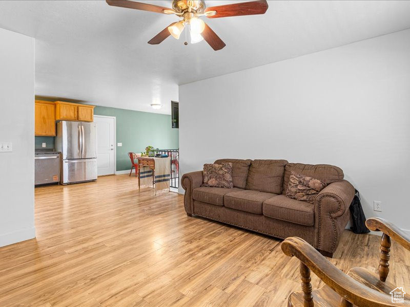 Living room with baseboards, a ceiling fan, and light wood-style flooring