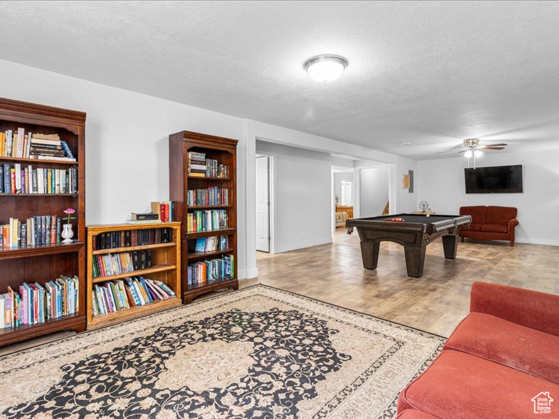 Playroom featuring a textured ceiling, baseboards, a ceiling fan, wood finished floors, and pool table
