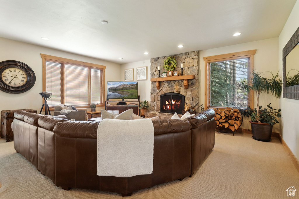 Living area with light carpet, recessed lighting, a stone fireplace, and plenty of natural light