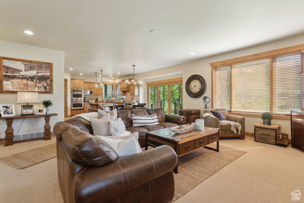 Living room featuring light colored carpet, recessed lighting, and a chandelier
