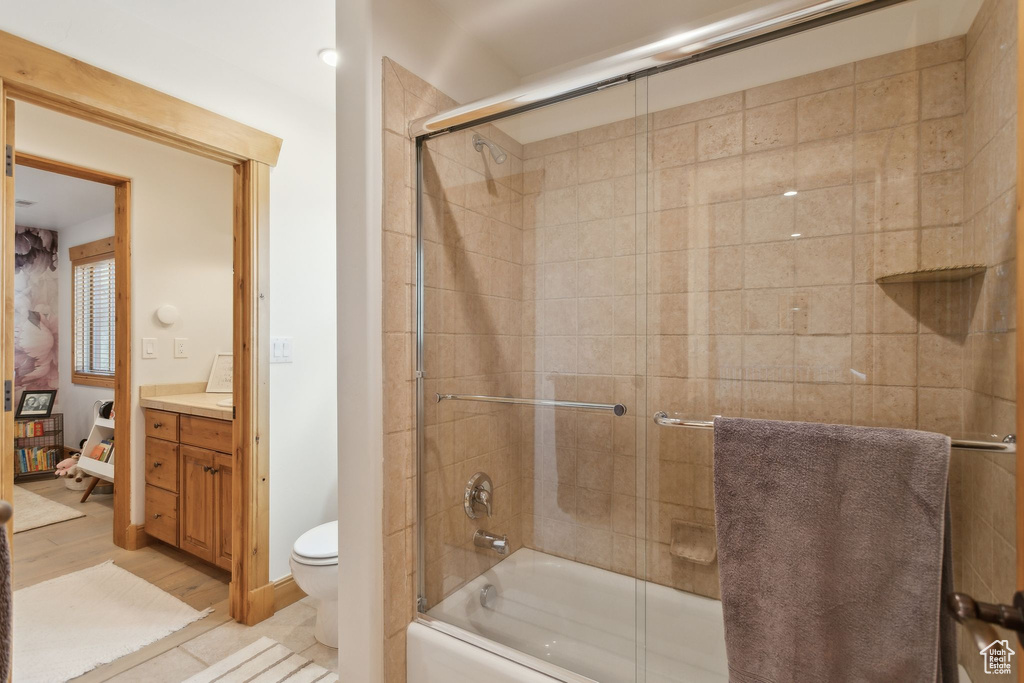 Bathroom featuring vanity, toilet, shower / bath combination with glass door, and wood finished floors