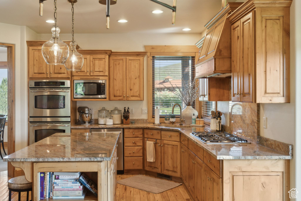 Kitchen featuring appliances with stainless steel finishes, a sink, light wood finished floors, custom exhaust hood, and recessed lighting