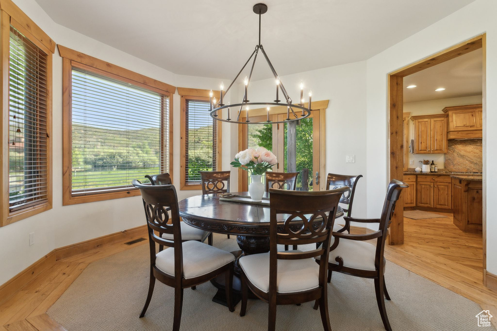 Dining room with a chandelier, light wood finished floors, baseboards, and recessed lighting
