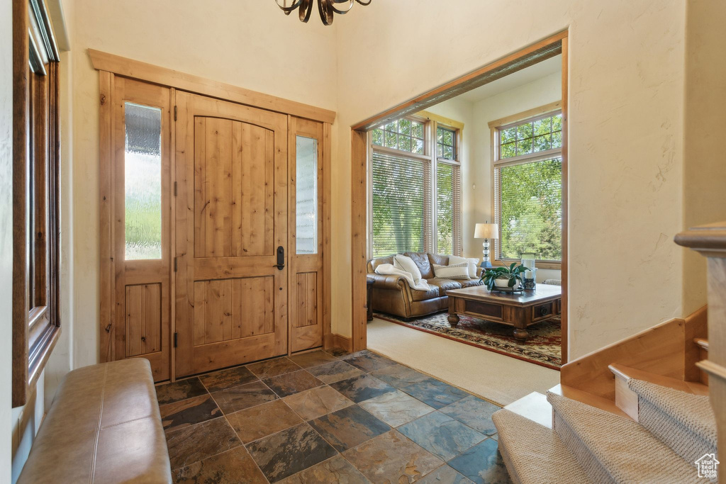 Foyer entrance featuring stone tile flooring, healthy amount of natural light, and a chandelier