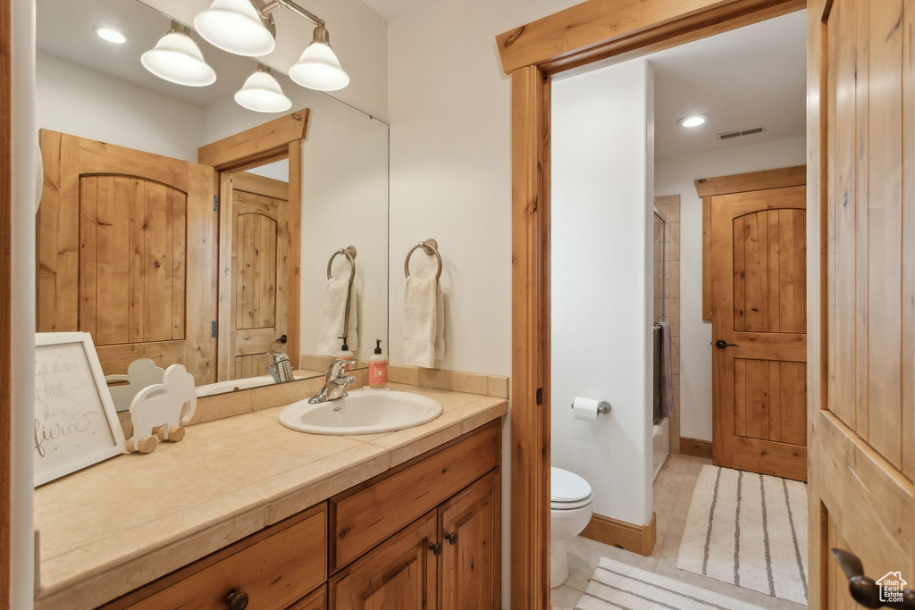 Full bath featuring toilet, vanity, shower / bath combination with glass door, recessed lighting, and tile patterned flooring
