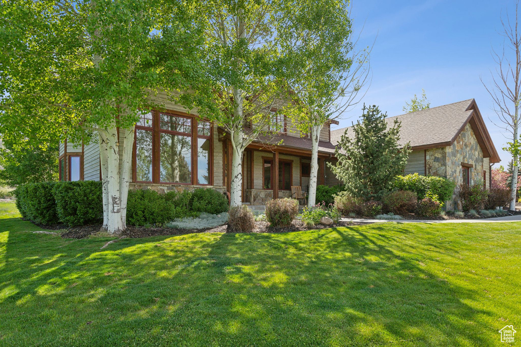 Obstructed view of property with stone siding and a front lawn