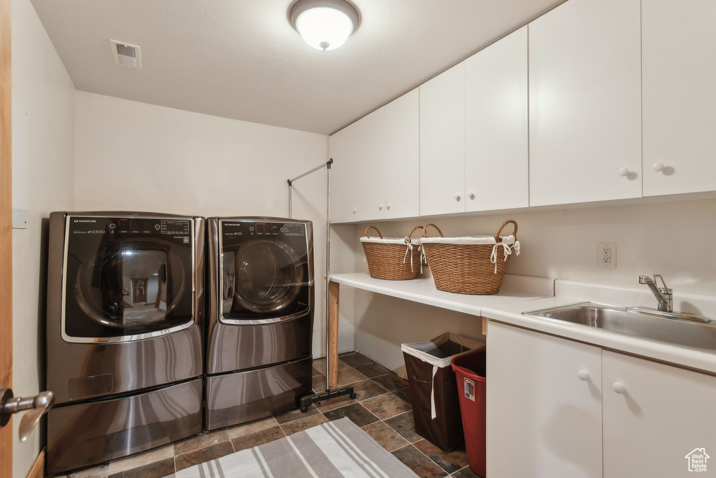 Washroom featuring cabinet space, washer and clothes dryer, and dark stone finish flooring