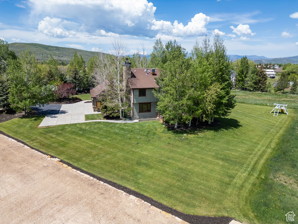 View of front of property with a chimney, a mountain view, and a front lawn