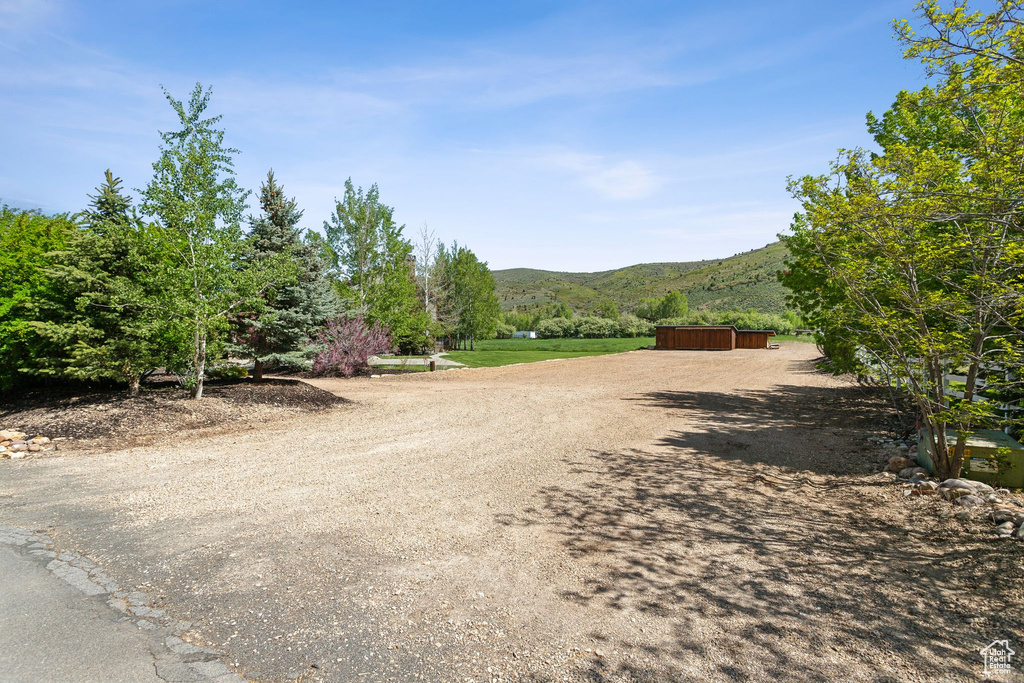 View of dirt / gravel road with a mountain view and an outbuilding