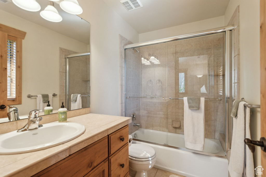 Full bath featuring toilet, vanity, shower / bath combination with glass door, and tile patterned flooring