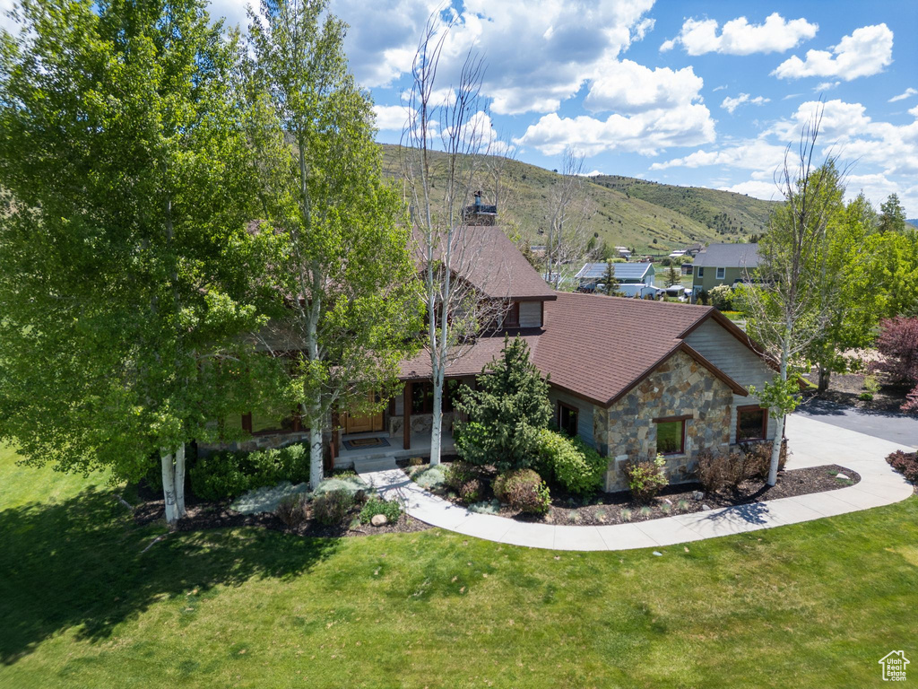 View of front facade with stone siding, a mountain view, a front lawn, and covered porch