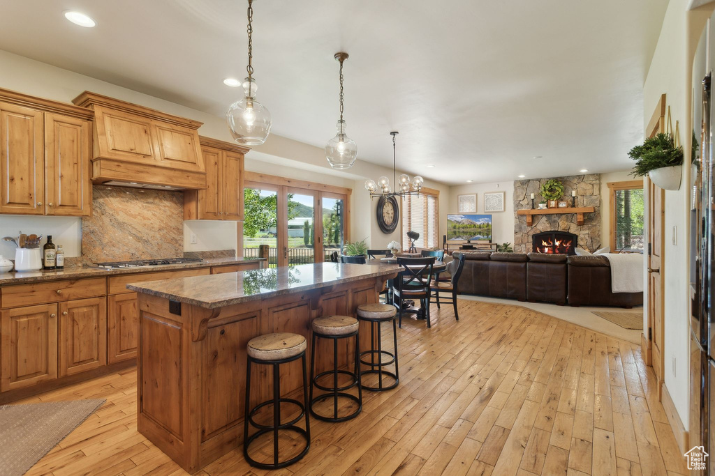 Kitchen with a center island, gas cooktop, light wood finished floors, backsplash, and recessed lighting