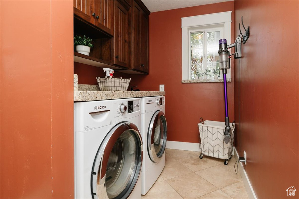 Laundry room with washing machine and dryer, baseboards, light tile patterned floors, and cabinet space