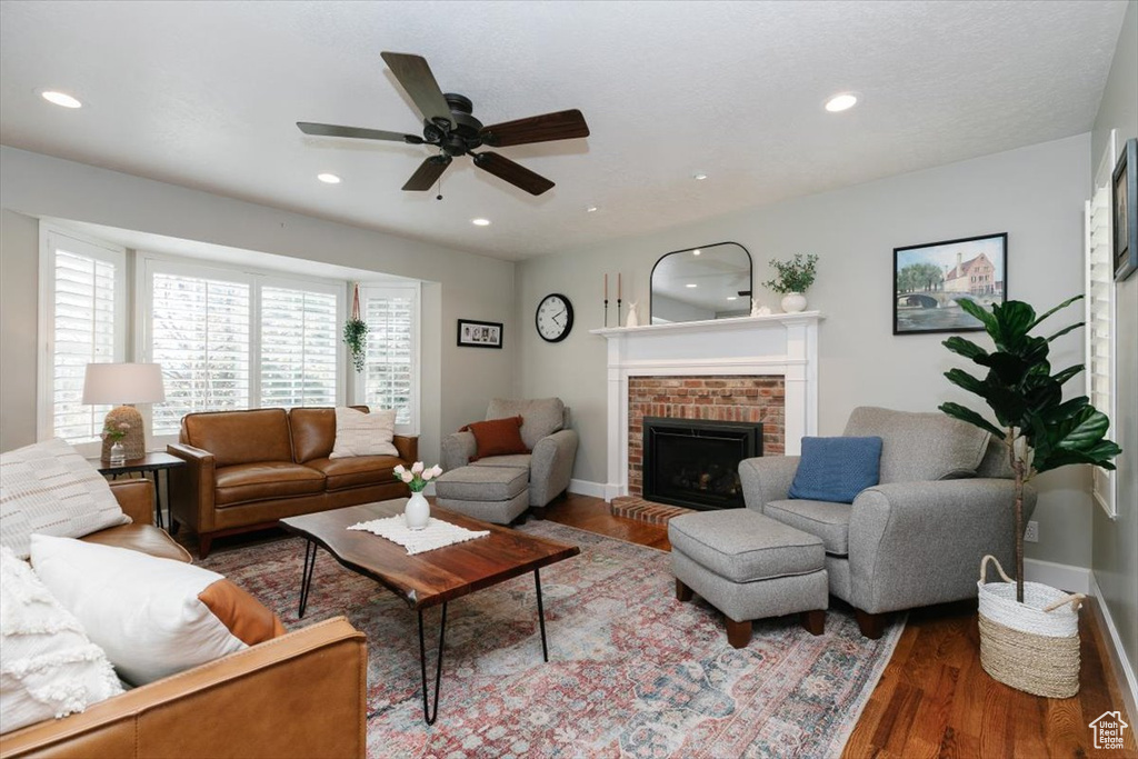Living area with baseboards, recessed lighting, a brick fireplace, wood finished floors, and ceiling fan