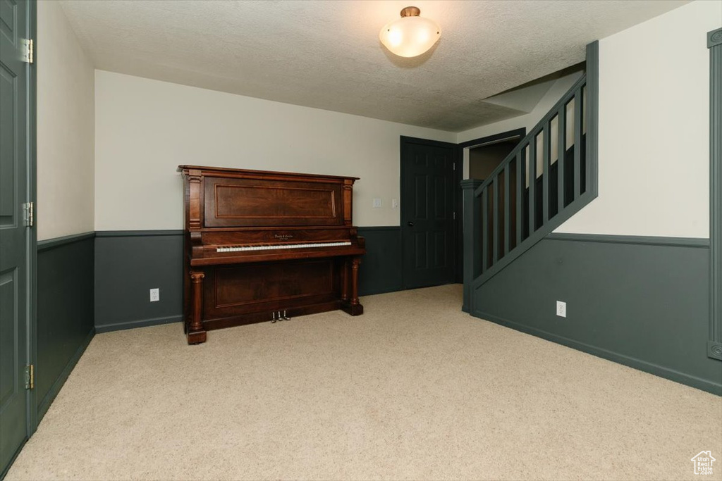 Living area featuring carpet floors, stairs, and a textured ceiling