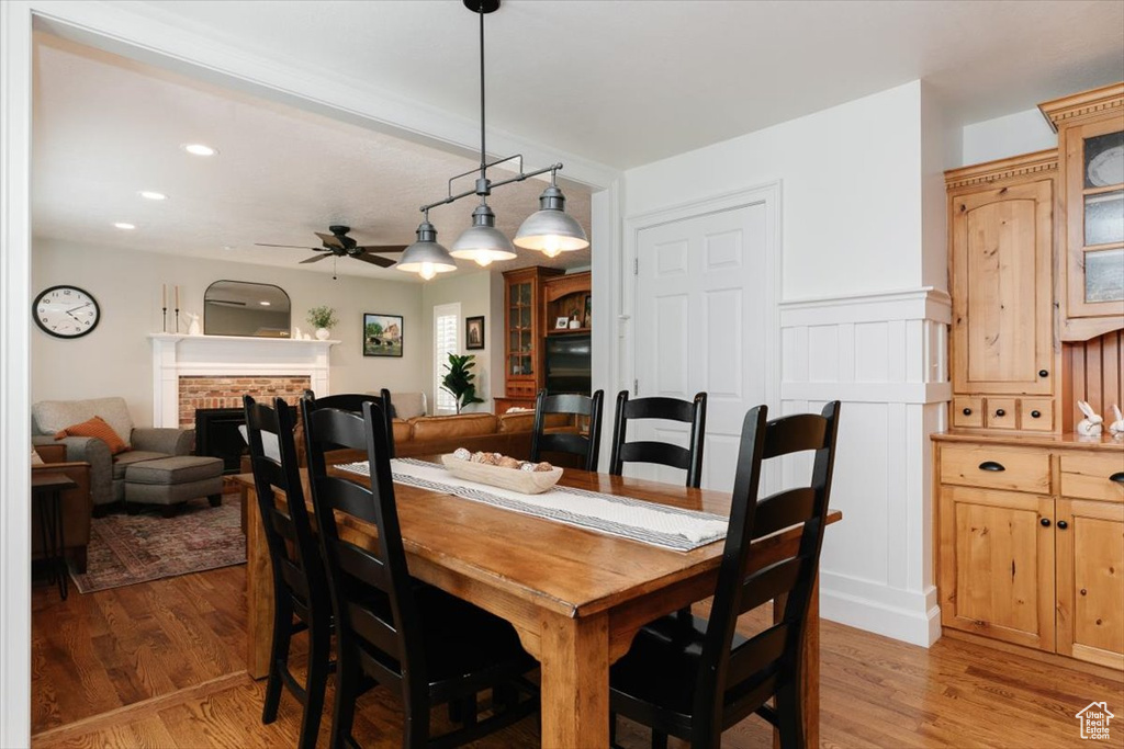 Dining space featuring light wood finished floors, a ceiling fan, a fireplace, and recessed lighting