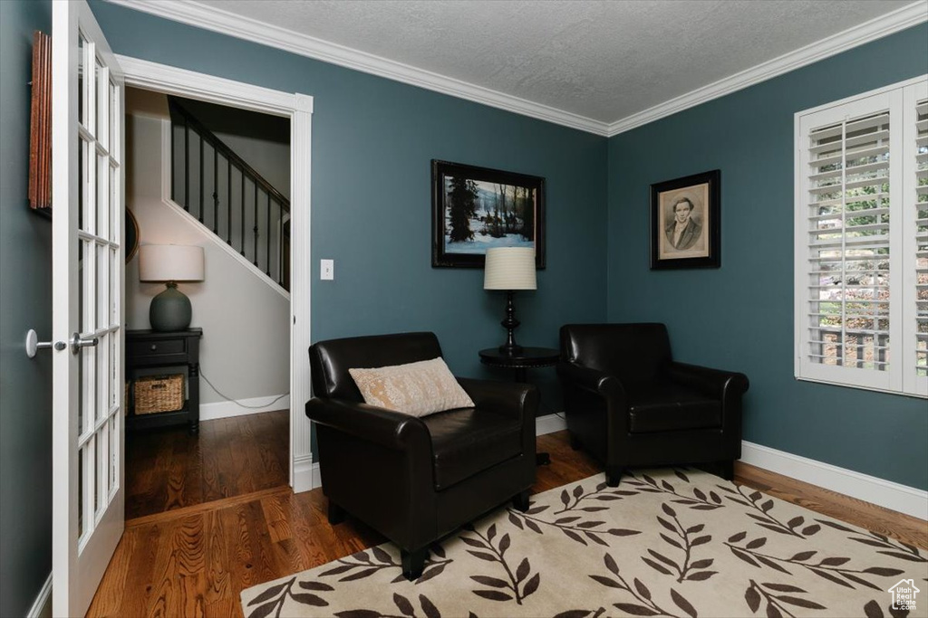Living area featuring wood finished floors, a textured ceiling, baseboards, and ornamental molding