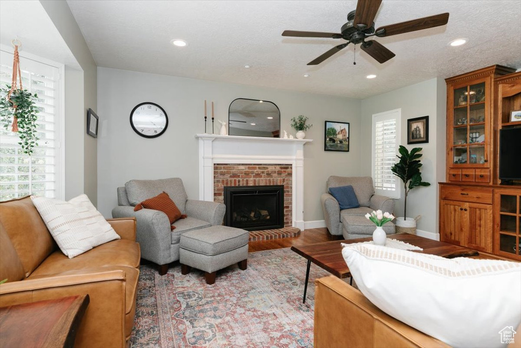 Living area featuring a fireplace, wood finished floors, a ceiling fan, and recessed lighting