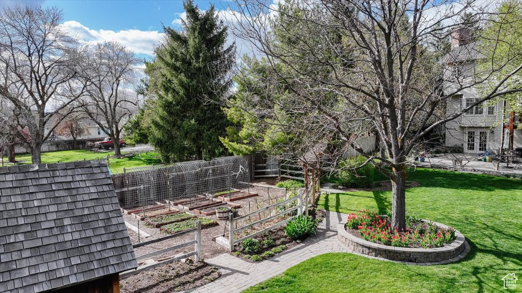 View of property\'s community featuring a lawn, a vegetable garden, and fence
