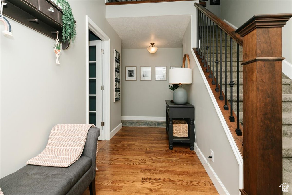 Entryway with baseboards, wood finished floors, and stairway