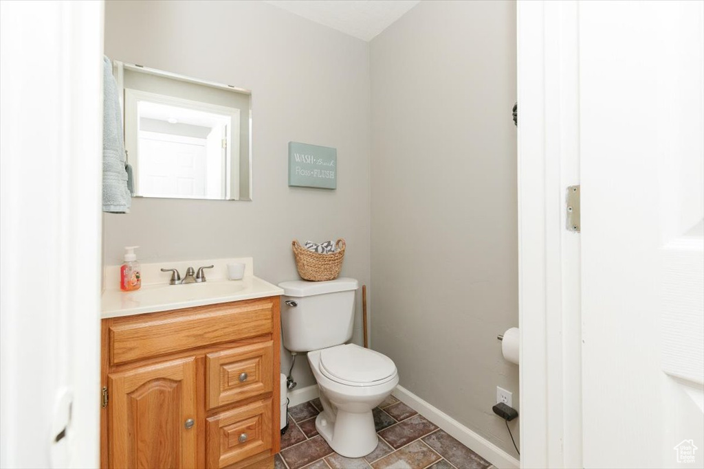 Half bath with baseboards, vanity, and toilet