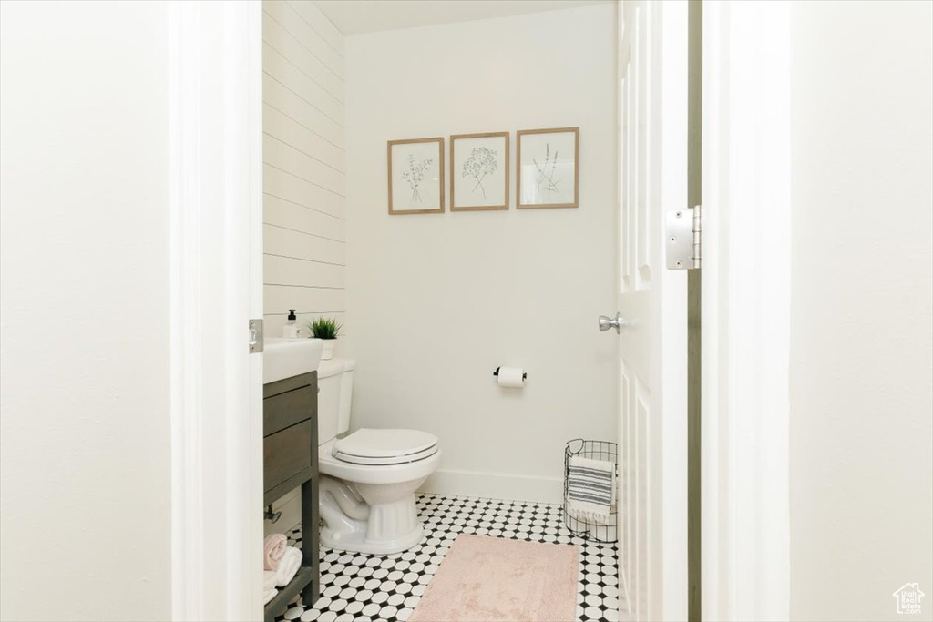 Half bathroom featuring baseboards, tile patterned flooring, vanity, and toilet