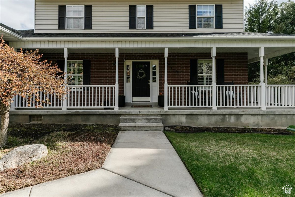 Entrance to property featuring brick siding and a porch