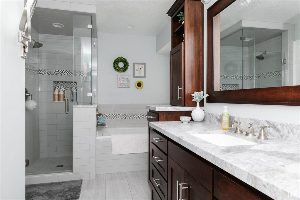 Bathroom with a shower stall, a bath, vanity, and tile patterned floors