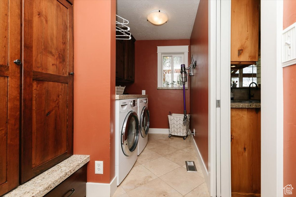 Laundry room with light tile patterned flooring, cabinet space, baseboards, visible vents, and independent washer and dryer