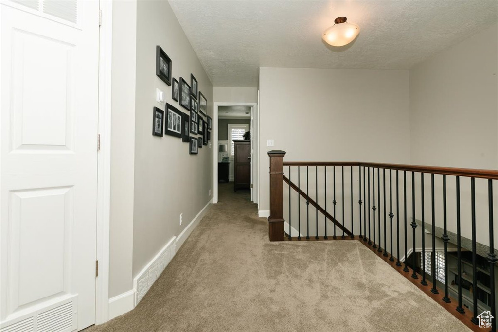 Hall with baseboards, visible vents, carpet floors, and an upstairs landing