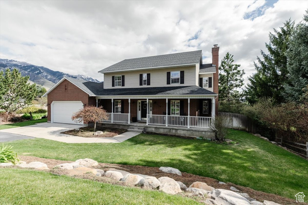 View of front of house with a chimney, concrete driveway, an attached garage, a porch, and a front yard