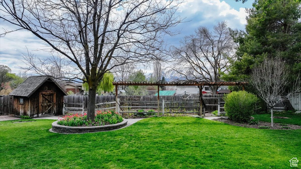 View of yard with an outdoor structure, fence, and a shed