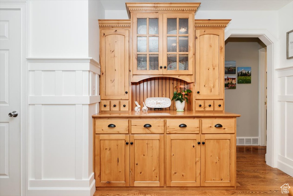 Interior space with light countertops, visible vents, light brown cabinets, glass insert cabinets, and light wood-style flooring