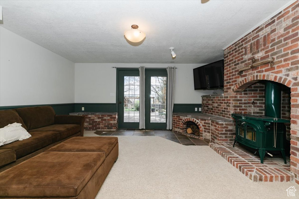 Living area with a wainscoted wall, carpet floors, a textured ceiling, and a wood stove