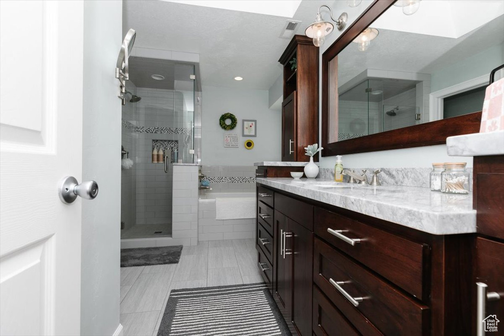 Bathroom with a shower stall, vanity, visible vents, and a tub