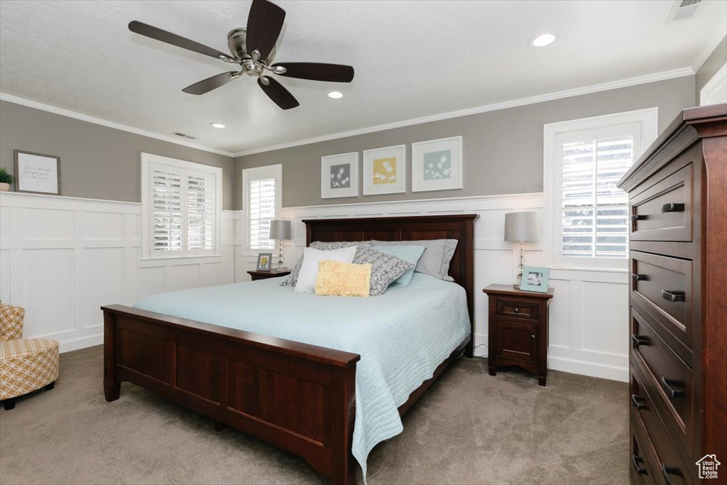 Bedroom with a wainscoted wall, light colored carpet, and a decorative wall