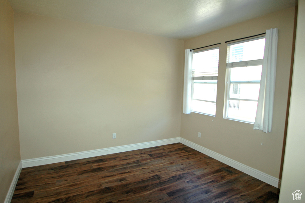 Unfurnished room with baseboards and dark wood-style flooring