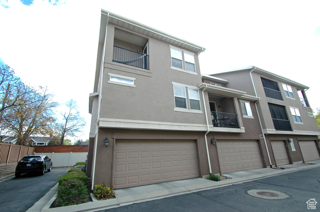 Townhome / multi-family property with a garage, stucco siding, and fence