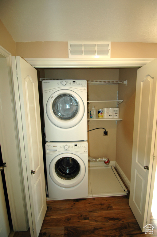 Laundry room featuring laundry area, visible vents, stacked washer / dryer, and wood finished floors