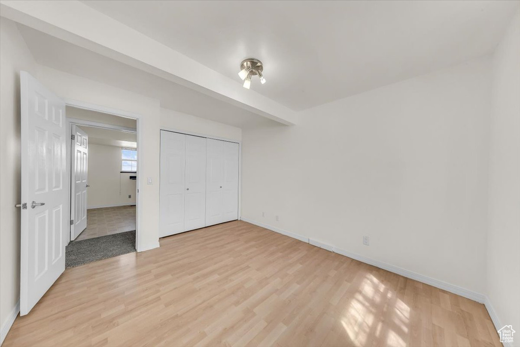 Unfurnished bedroom with light wood-type flooring, baseboards, and a closet