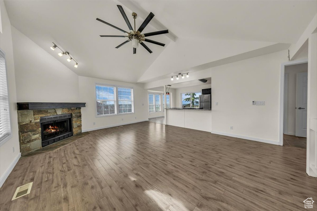 Unfurnished living room with track lighting, wood finished floors, visible vents, lofted ceiling with beams, and ceiling fan