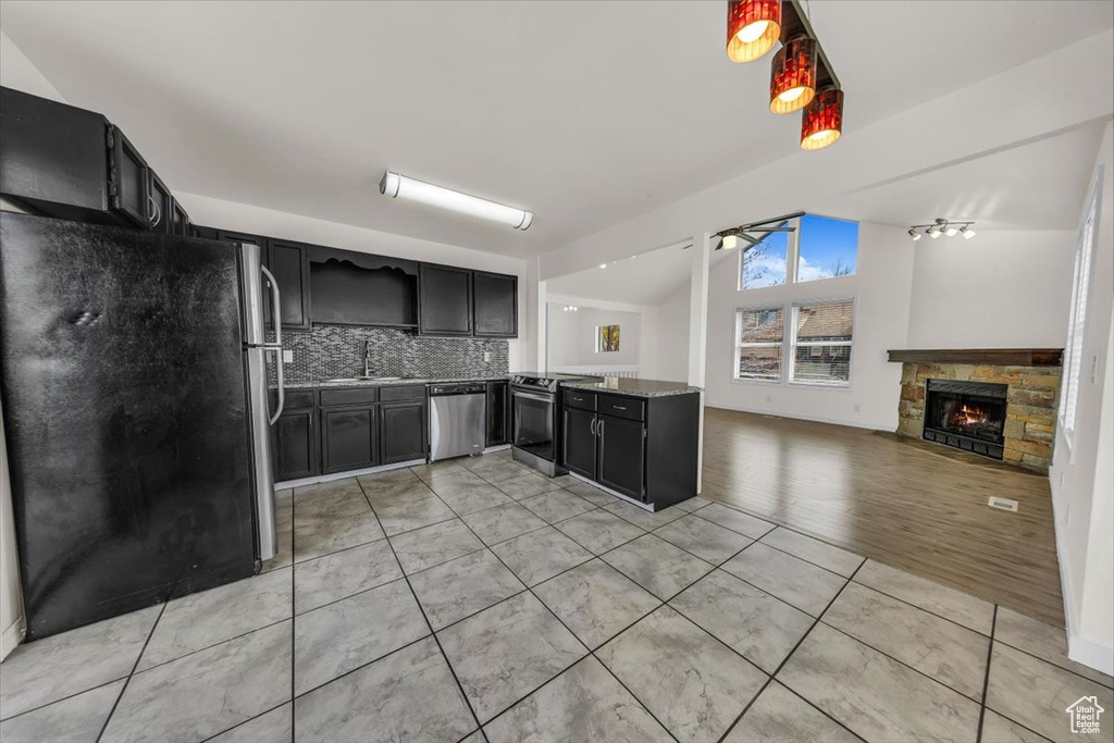Kitchen with stainless steel appliances, dark cabinets, a sink, decorative backsplash, and a peninsula