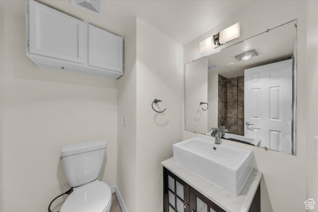 Bathroom featuring toilet, vanity, visible vents, and baseboards