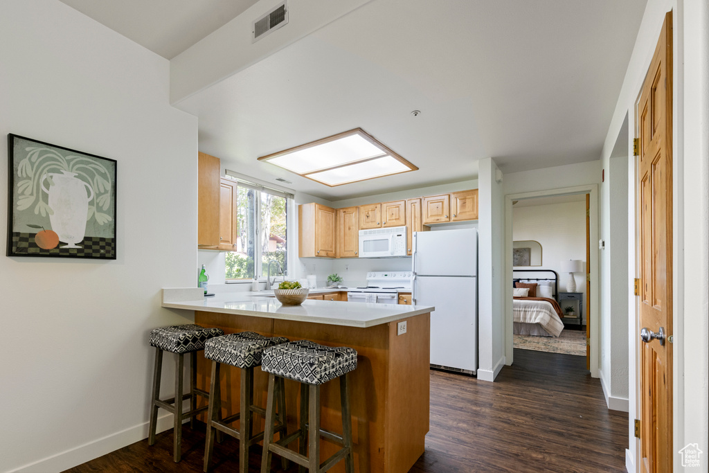 Kitchen featuring white appliances, a peninsula, baseboards, light countertops, and dark wood finished floors