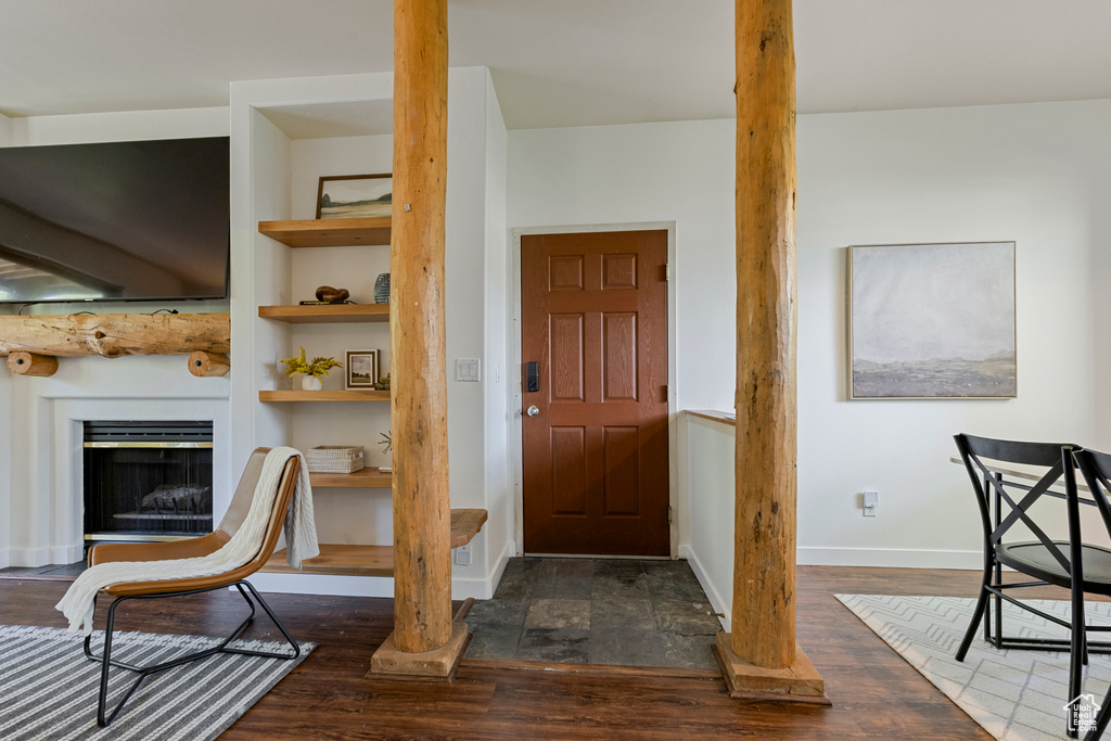 Foyer entrance with wood finished floors, baseboards, and a fireplace with raised hearth