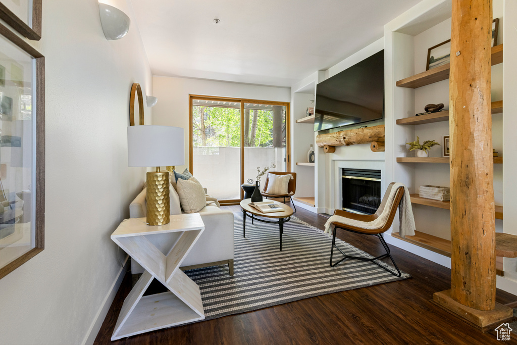Living room featuring wood finished floors, a fireplace, built in shelves, and baseboards