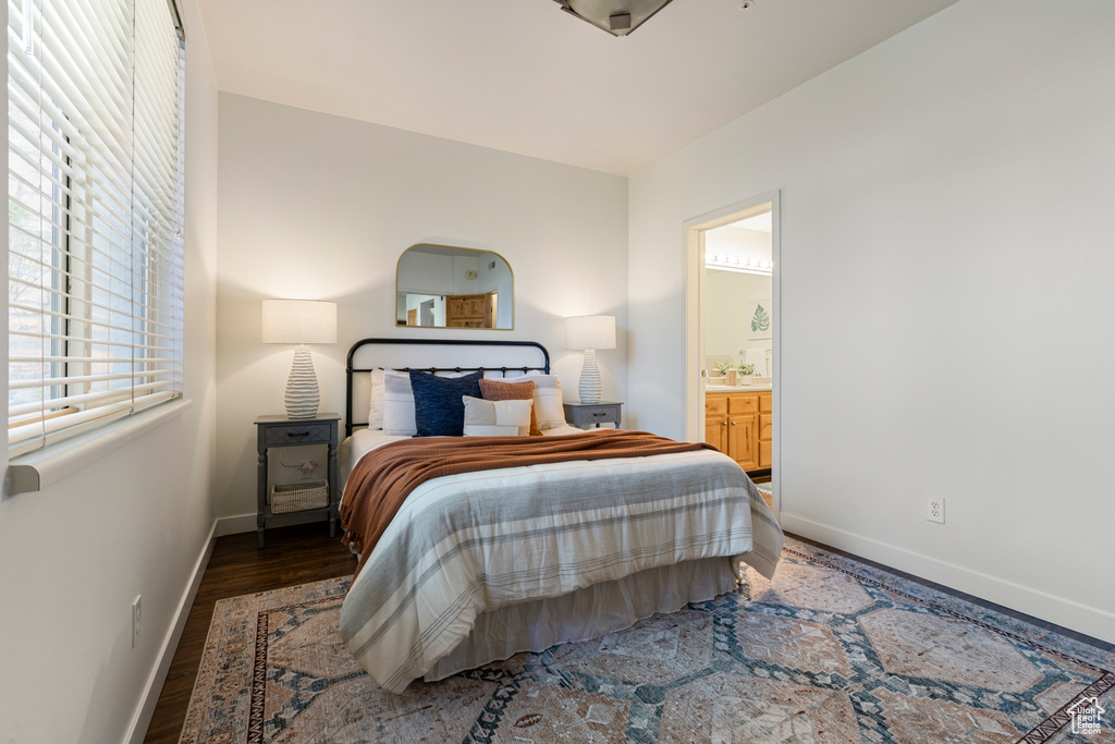 Bedroom featuring baseboards, wood finished floors, and ensuite bathroom