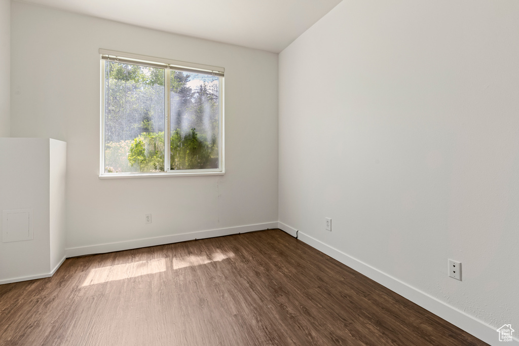 Spare room with dark wood-style flooring and baseboards