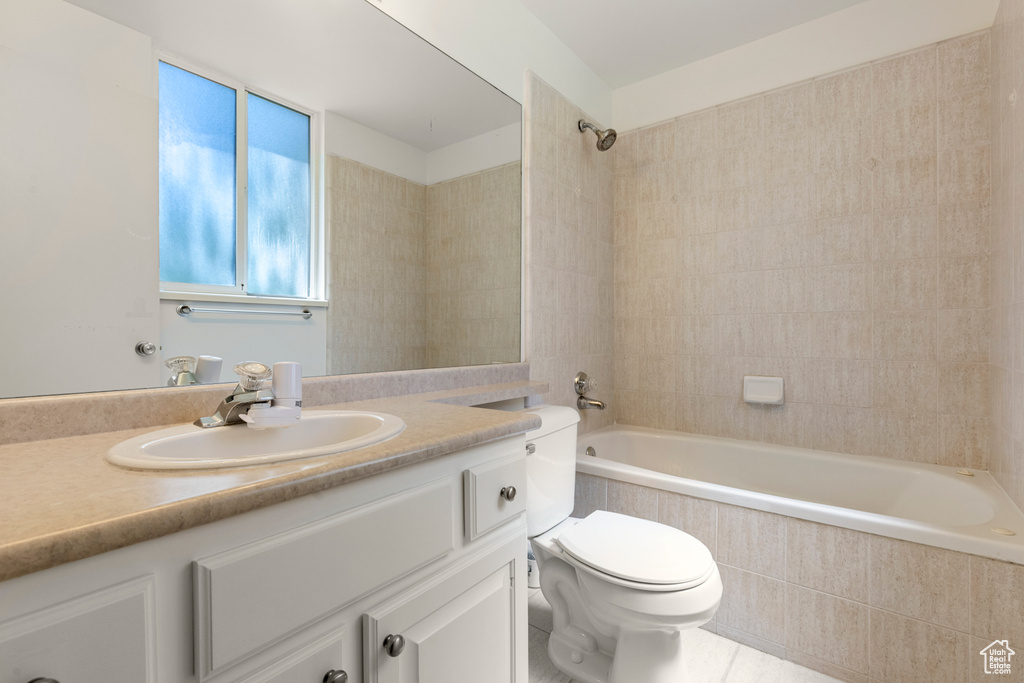 Bathroom with vanity, toilet, and tiled shower / bath combo